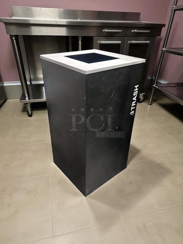Black commercial trash receptacle, unbranded, excellent condition, fully tested, ready for use, marked "TRASH" on side.