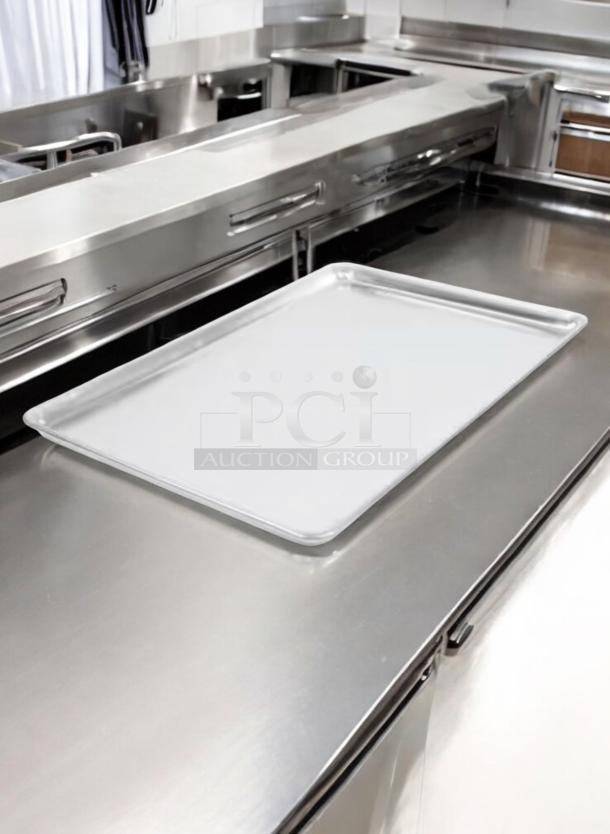 Commercial grade 18"x26" aluminum sheet pan in excellent condition on stainless steel counter. Quantity 45 available.
