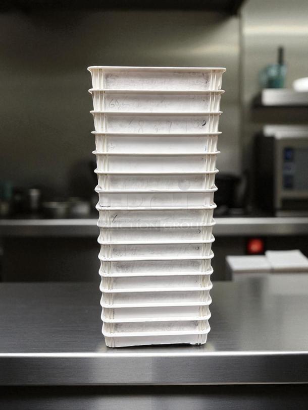 Stack of unbranded commercial dough trays, excellent condition, fully cleaned, ready for use, in a kitchen setting.