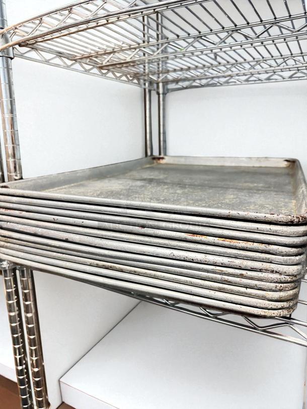 Set of commercial-grade full-size sheet pans in excellent condition, stacked on a metal rack, unbranded and ready for use.