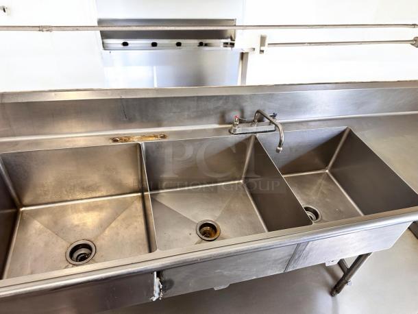 Commercial 3-compartment stainless steel sink with dual drainboards in excellent condition, fully tested and operational.