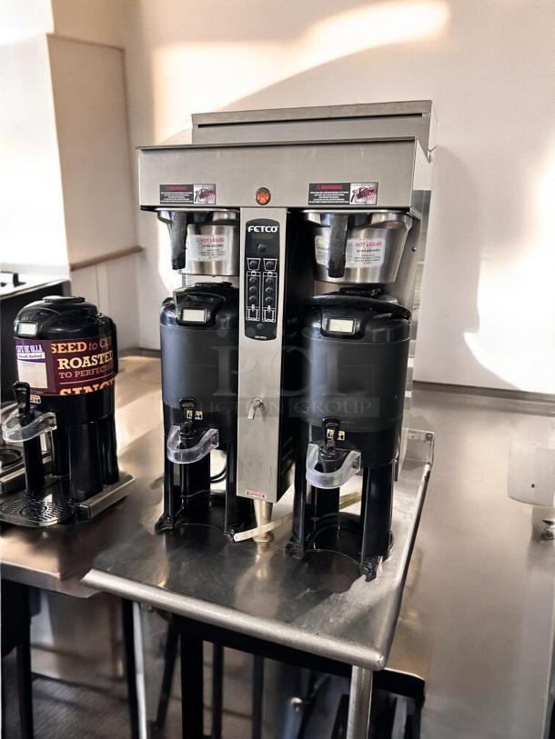 Fetco CBS-2052e dual coffee brewer, excellent condition, fully operational, stainless steel, visible control panel and hot liquid warnings.