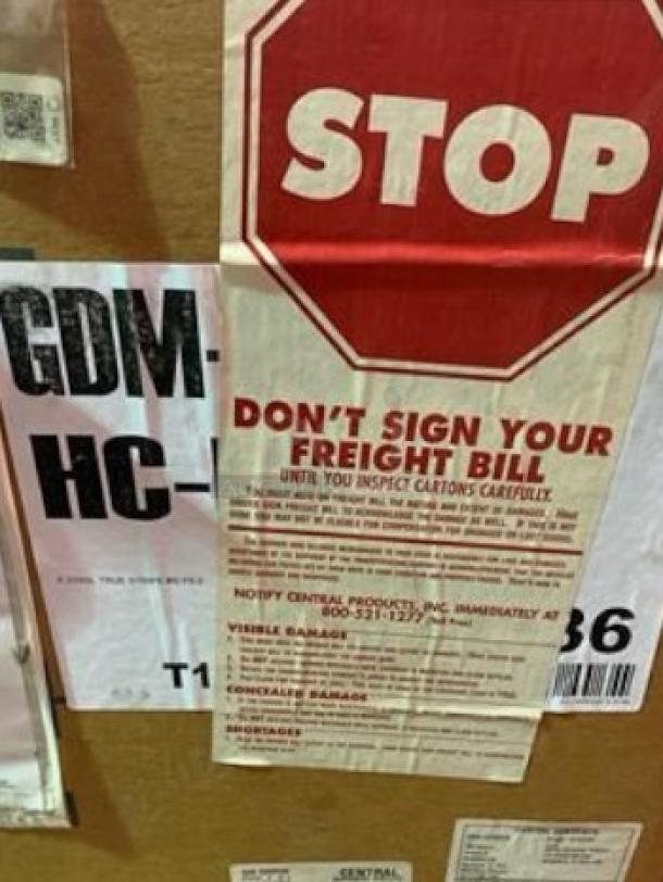 Brand new True GDM-HC double glass door merchandiser in sealed crate. Labels indicate caution for freight inspection.