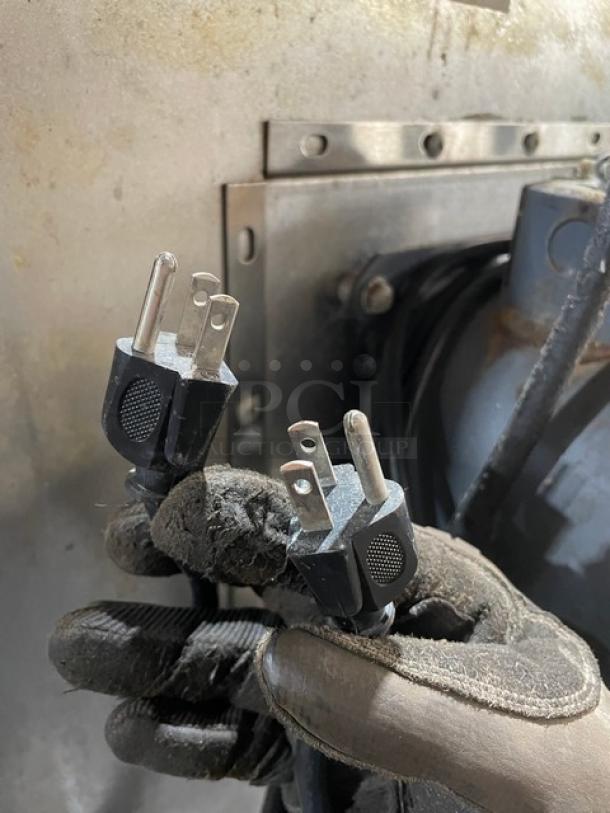 Gloved hand holding electrical plugs in front of industrial equipment, likely part of Southbend oven setup.