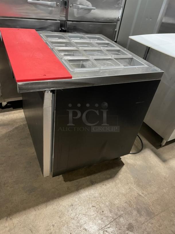 Continental Commercial Black Single Door Refrigerated Prep Table, Model SW32-12M, with red cutting board, clear food pans, and poly-coated wired rack, on casters.