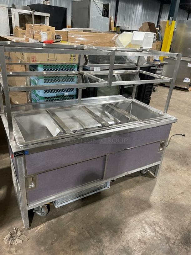 Atlas Metal stainless steel refrigerated buffet style 4-well cold salad bar. Model WCMBT4, with sneeze guard, tray slide, enclosed storage, and casters.