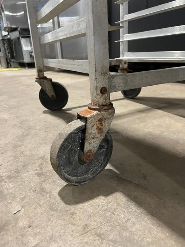 Commercial heavy-duty pan holding/transport rack on casters, metallic build, visible wear and rust, suitable for kitchen use.