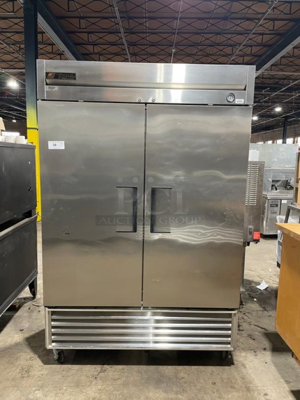 True T-49F commercial stainless steel 2-door reach-in freezer with poly-coated wire racks, 115V, on casters.