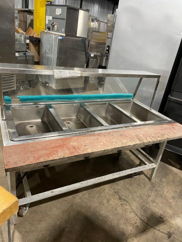 Atlas Metal stainless steel 4-well steam table with sneeze guard and tray slide, on casters, 208V, 1 phase, commercial use.