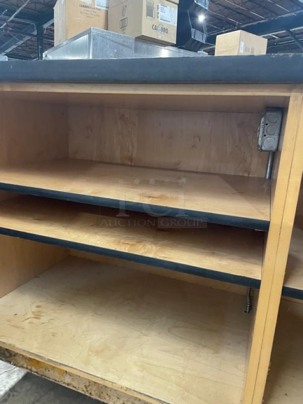 Custom wooden enclosed cabinet base with multi-level shelving, visible power outlet, commercial use, good condition.