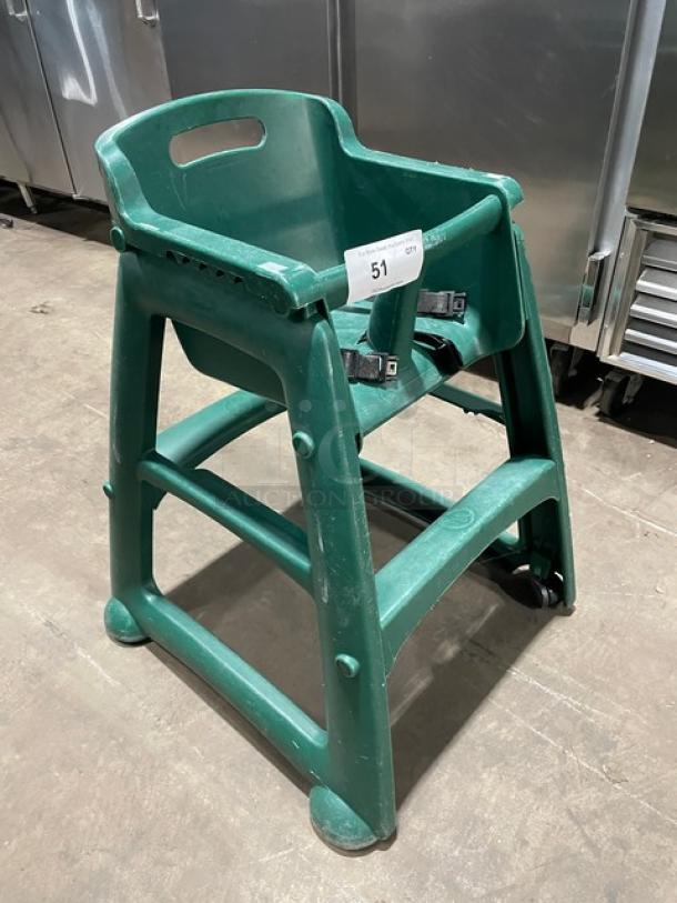 Green commercial stackable highchair with strap and buckles on casters, in used condition.
