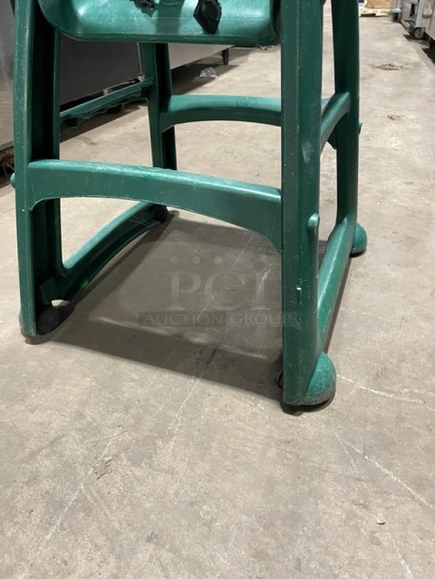 Green commercial stackable highchair with strap, buckles, and casters. Durable plastic construction, suitable for restaurants.