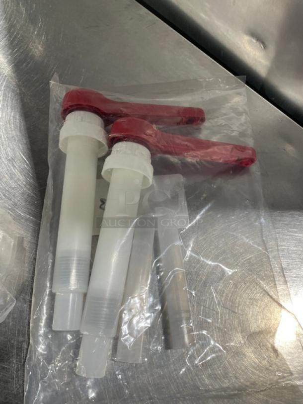 Brand new commercial red condiment pump set in original packaging, featuring two pumps with red handles and clear bodies.