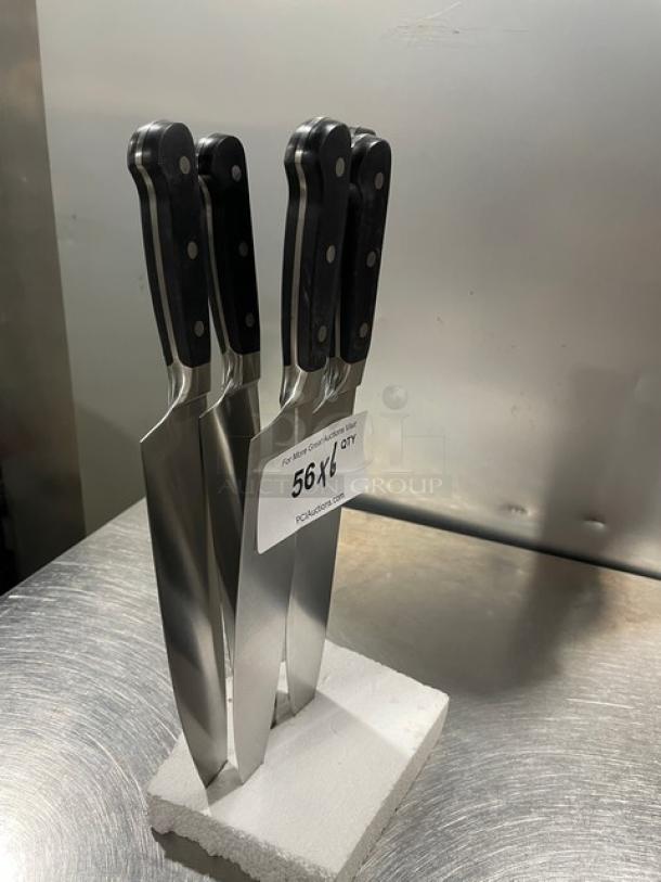 Set of new commercial stainless steel chef knives with black grip handles, displayed upright. Tag shows "56X" quantity.