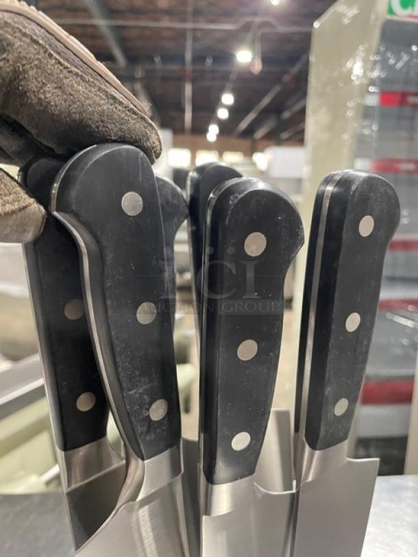 New commercial stainless steel chef knives with black grip handles, riveted design, pristine condition.