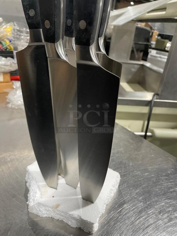 New commercial stainless steel chef knives with black grip handles, set of three, pristine condition, displayed on styrofoam.