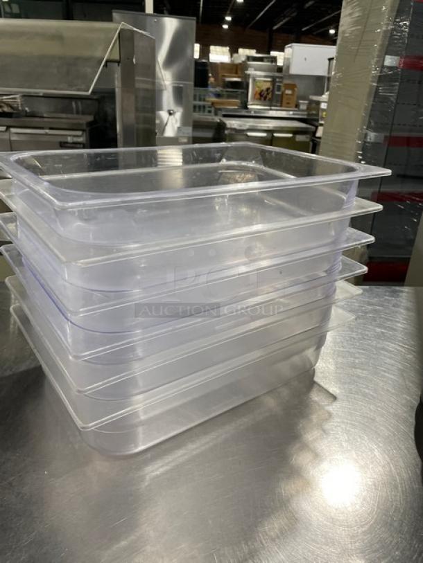 Stack of commercial clear polycarbonate food pans, unused. Set of six, durable material, standard size, ideal for kitchens.