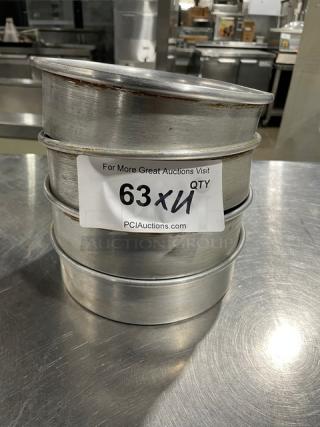 Stack of four commercial round baking pans with minor wear. Includes a paper label indicating auction information and quantity.