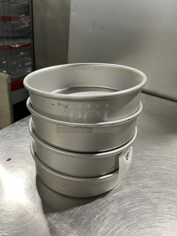 Four commercial round baking/stacking pans, metallic, lightly used, suitable for professional kitchen use, visible markings on side.