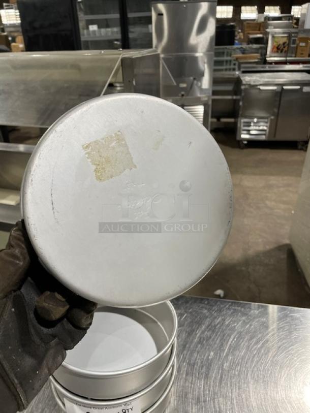 Commercial round baking/stacking pan, aluminum, gently used, visible label residue, stack of four pans included.