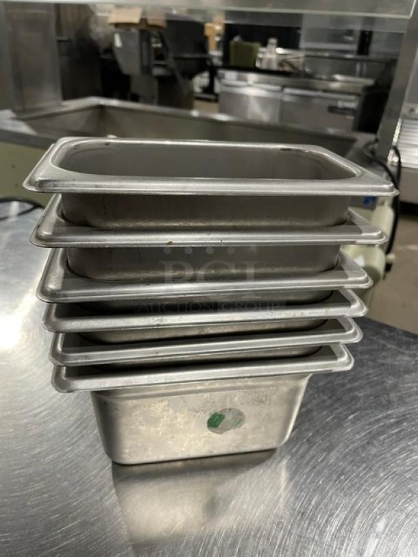 Don commercial stainless steel steamtable pans, stacked, lightly used, durable for hotel kitchen use, 6 pieces.