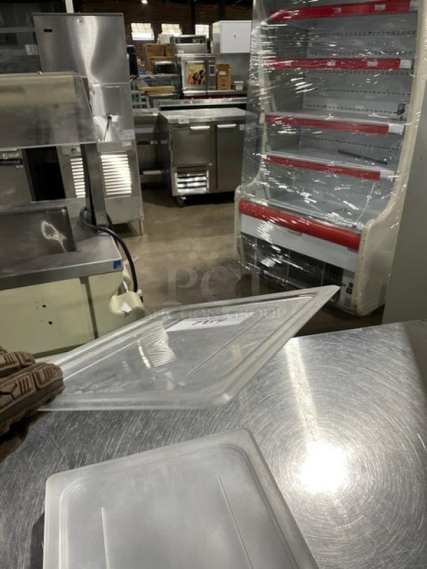 Cambro clear polycarbonate food pan lid, commercial quality, shown on a metal surface. Auction tag visible.