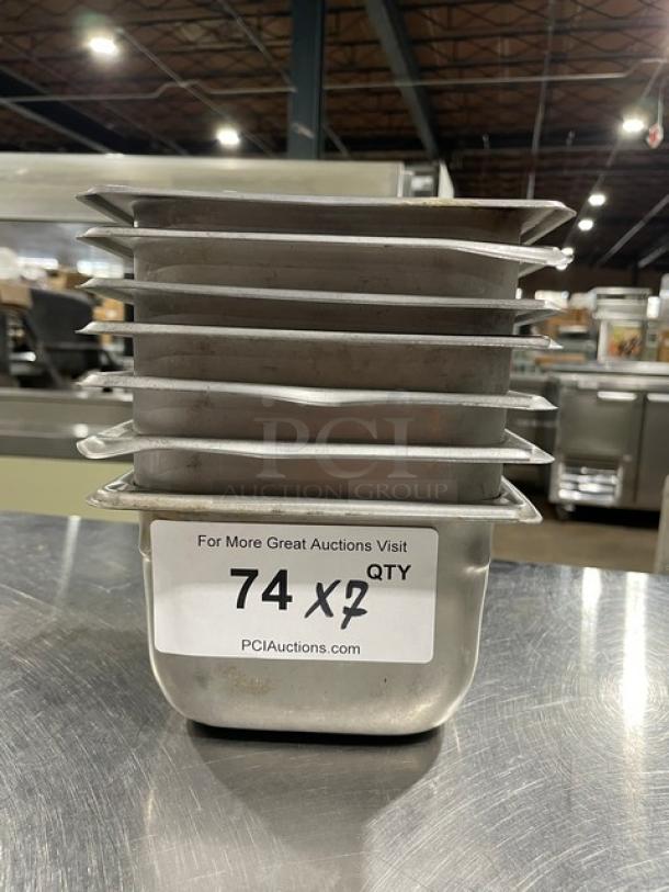 Stack of seven commercial stainless steel hotel pans, used condition, with auction label "74 X 7" from PCIAuctions.com.