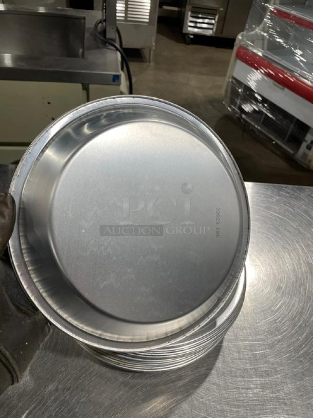 Stack of commercial round pie pans, metal, pristine condition, 19 total, marked "G00BB52G02" on surface.