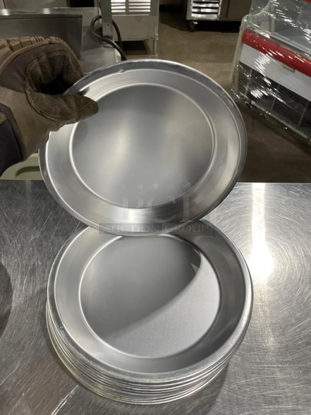 Commercial round pie pans, stack of 19, aluminum, smooth finish, industrial setting, auction item.
