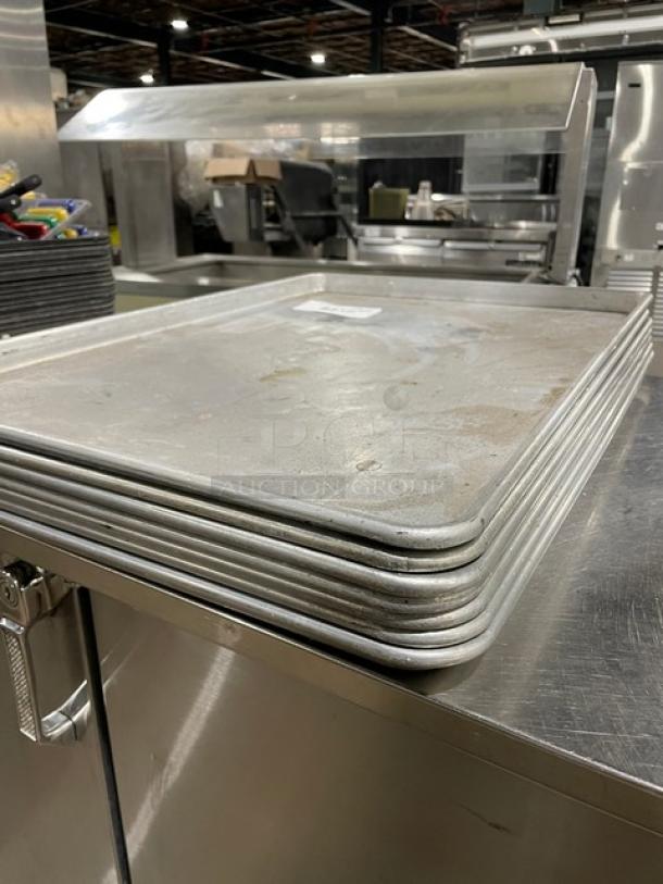 Commercial rectangular baking sheet pans, stacked, used condition, metal finish, suitable for large-scale baking.