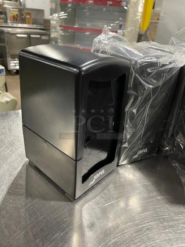 Jofel black countertop tall-fold napkin dispenser, on legs, new condition, features Jofel logo, ideal for commercial use.
