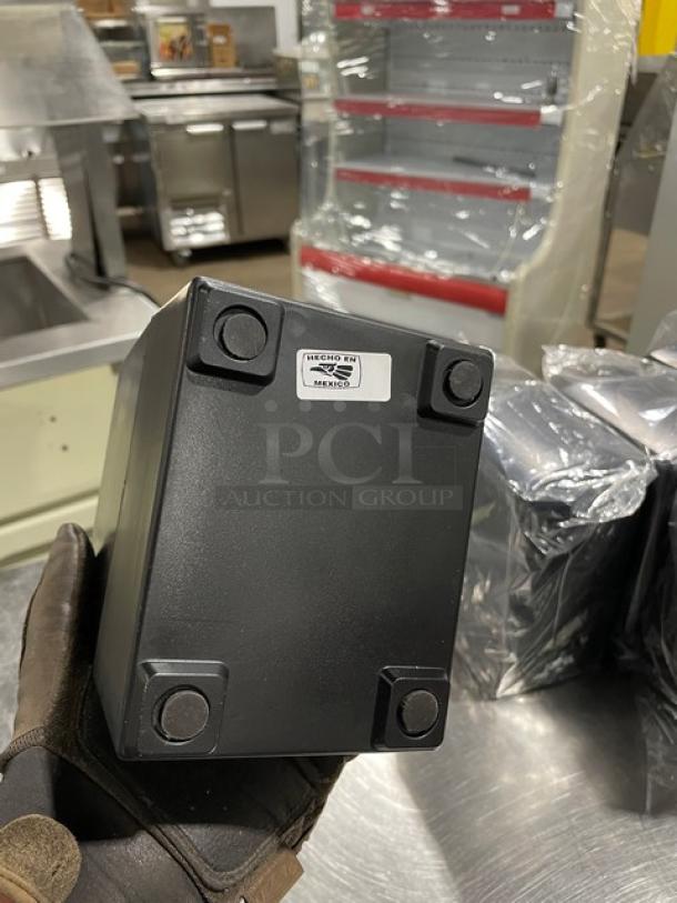 NEW Jofel black tabletop tall-fold napkin dispenser, on legs, shown from bottom with label indicating "Made in Mexico".