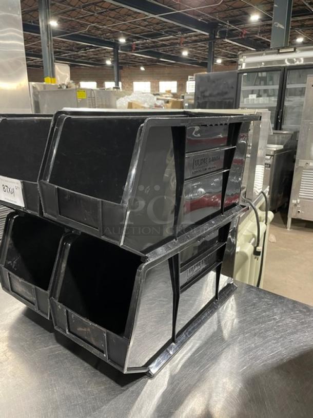 Stackable black countertop condiment/utensil organizing bins in good condition on metal surface, two tiers, warehouse setting.