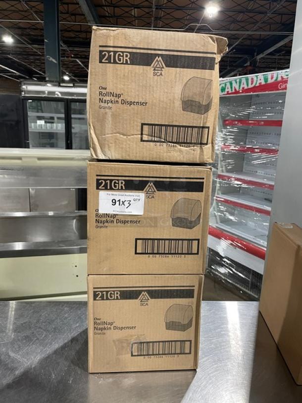 SCA Model 21GR granite napkin dispensers in boxes, brand new. Three stacked boxes. Labels show model and barcode.