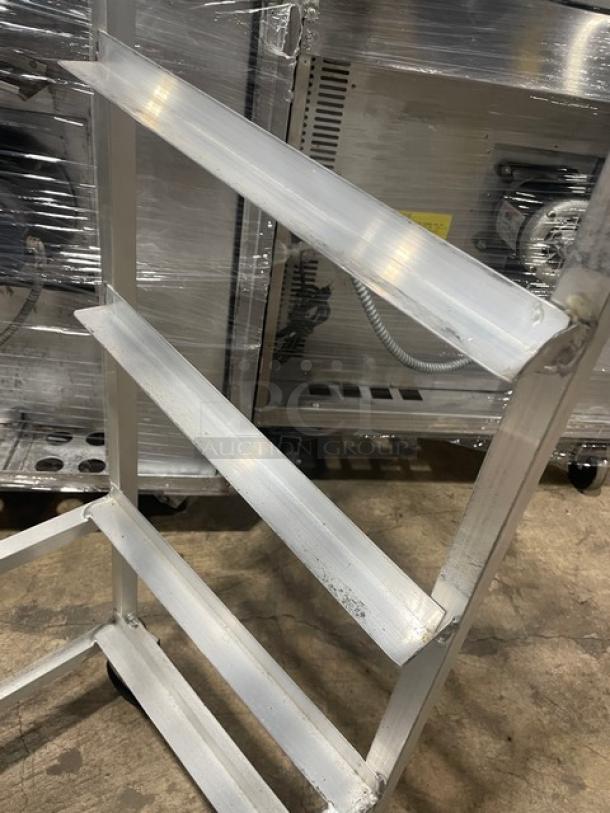 Channel SRS-7 aluminum slanted display rack on casters, commercial use, sturdy frame, signs of wear, three shelves.