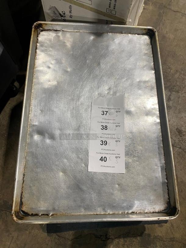 Commercial full-size baking sheet pan, used condition, some wear and discoloration. Auction lot details visible on paper sheet.