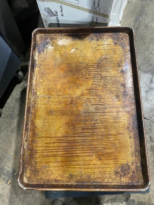 Commercial full-size baking sheet pan, well-used with visible scratches and discoloration, durable for heavy-duty baking.