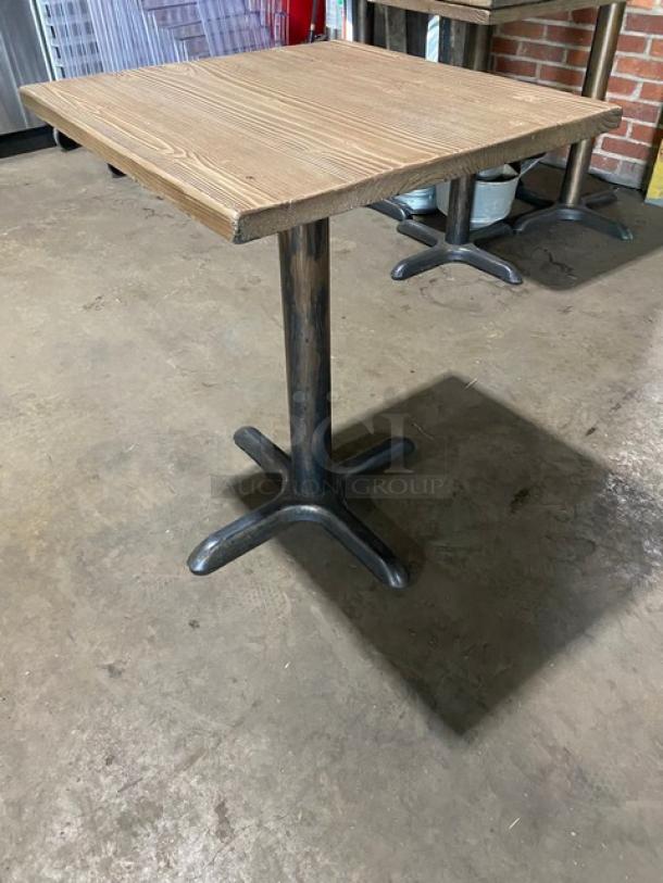 Commercial wooden square dining table with black metal base, good condition. Ideal for restaurants or cafes.