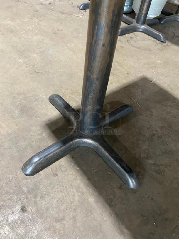 Commercial wooden square dining table with black base, minor wear, sturdy construction, ideal for restaurant use.