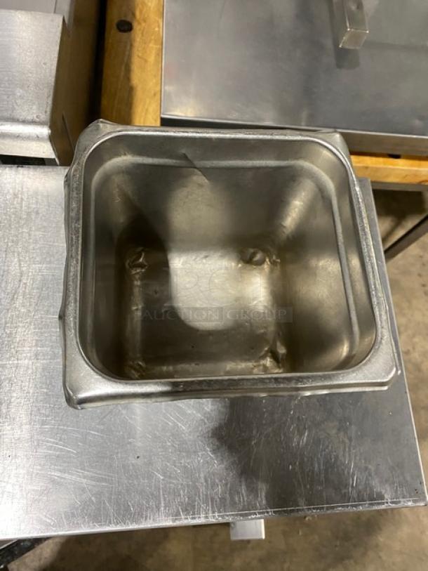 Commercial stainless steel hotel/steamtable pan, square shape, used condition, visible dents, ideal for catering or food service.