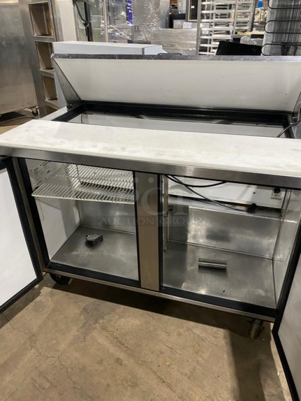 True TSSU-48-12 2-door refrigerated prep table, stainless steel, with cutting board and poly-coated wired rack, on casters.
