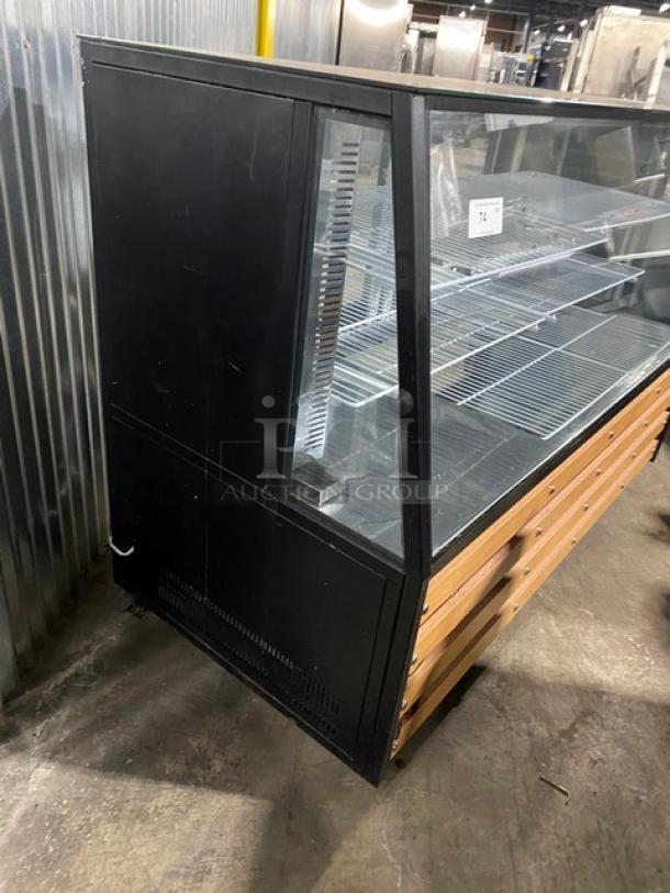 Commercial black 72" slanted glass refrigerated deli merchandiser with lower storage, dual sliding doors, poly racks, on casters.