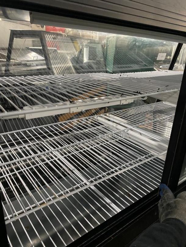 Commercial 72" black refrigerated meat deli merchandiser with slanted glass, poly coated racks, and lower storage compartment.
