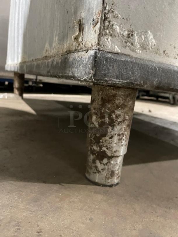 Manitowoc stainless steel ice machine on metal legs, showing signs of wear and rust. Model SY1804A/B970.