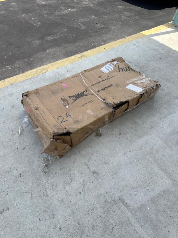 Cardboard box with visible damage, labeled "Regency 600WMTB3060" for a 30"x60" stainless steel table, shows shipping wear.