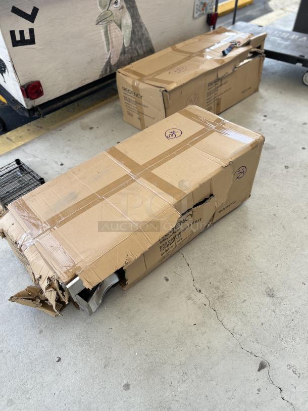 Damaged boxes containing Regency Stainless Steel Underbar Drainboard, model 600DBU2148. Visible branding and size details.