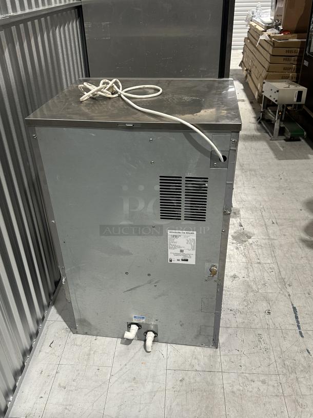 Used Hoshizaki Ice Maker, Model DCM-300BAH, Serial H23773K. Visible wear, metal exterior, two drain outlets, specification label.