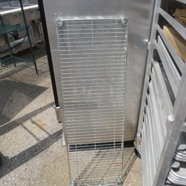 Metal Metro shelf, 42x14 inches, silver, in good condition, vertical wire grid design, outdoor setting.