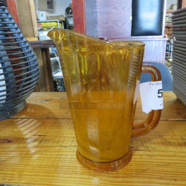 Amber poly pitcher with contoured handle and spout. Good condition. Auction tag visible.