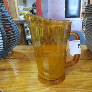 Amber poly pitcher with contoured handle and spout. Good condition. Auction tag visible.